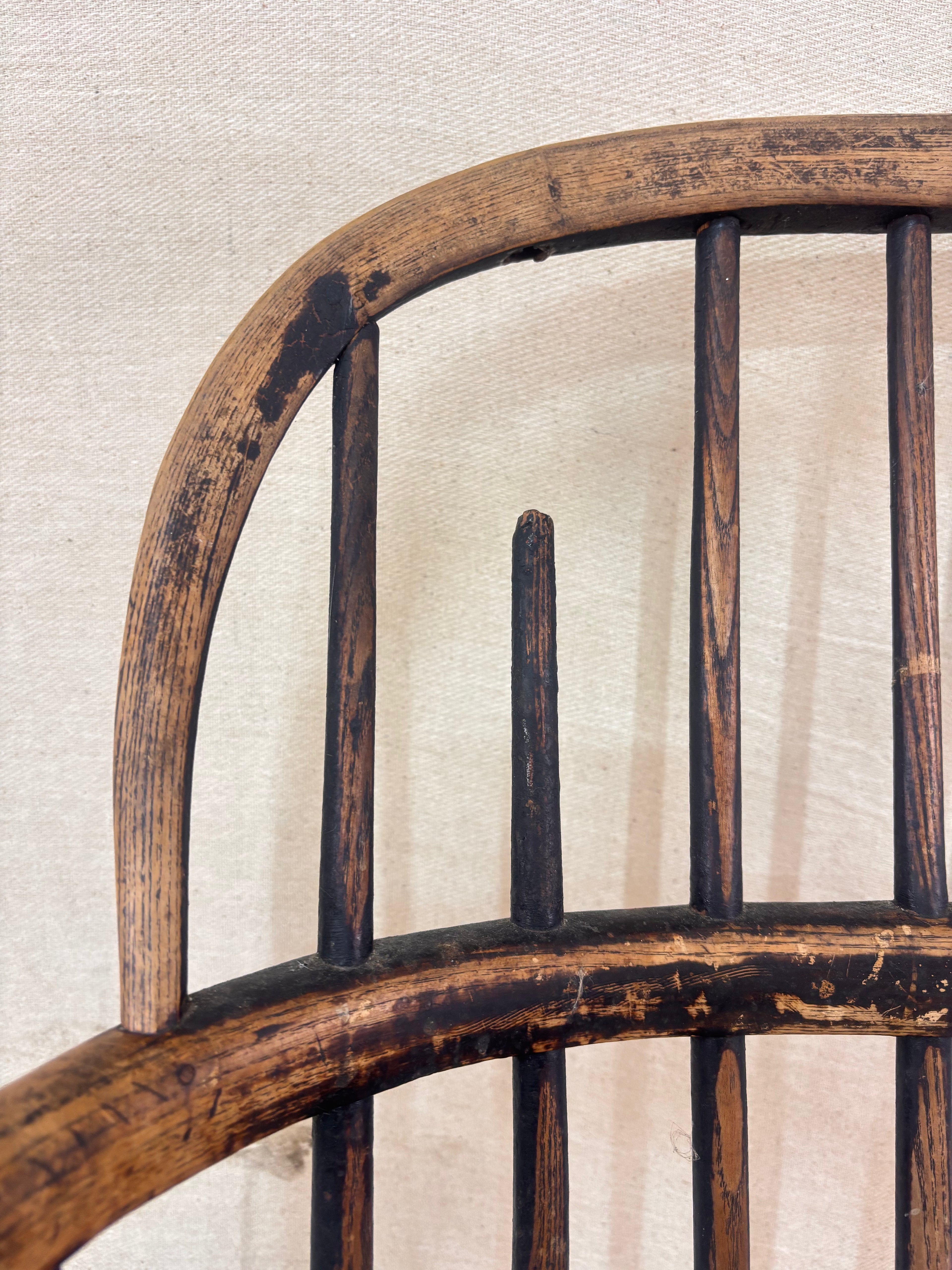 Windsor chair with hoop back, saddled seat, and splayed turned legs shown against a cream fabric background.