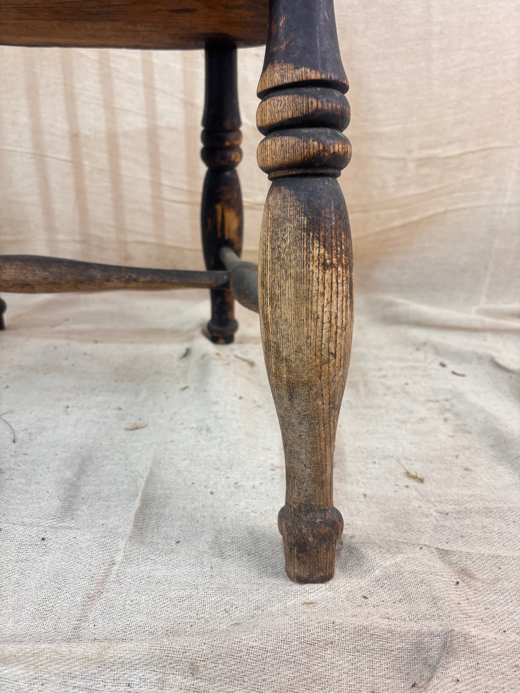 Windsor chair with hoop back, saddled seat, and splayed turned legs shown against a cream fabric background.