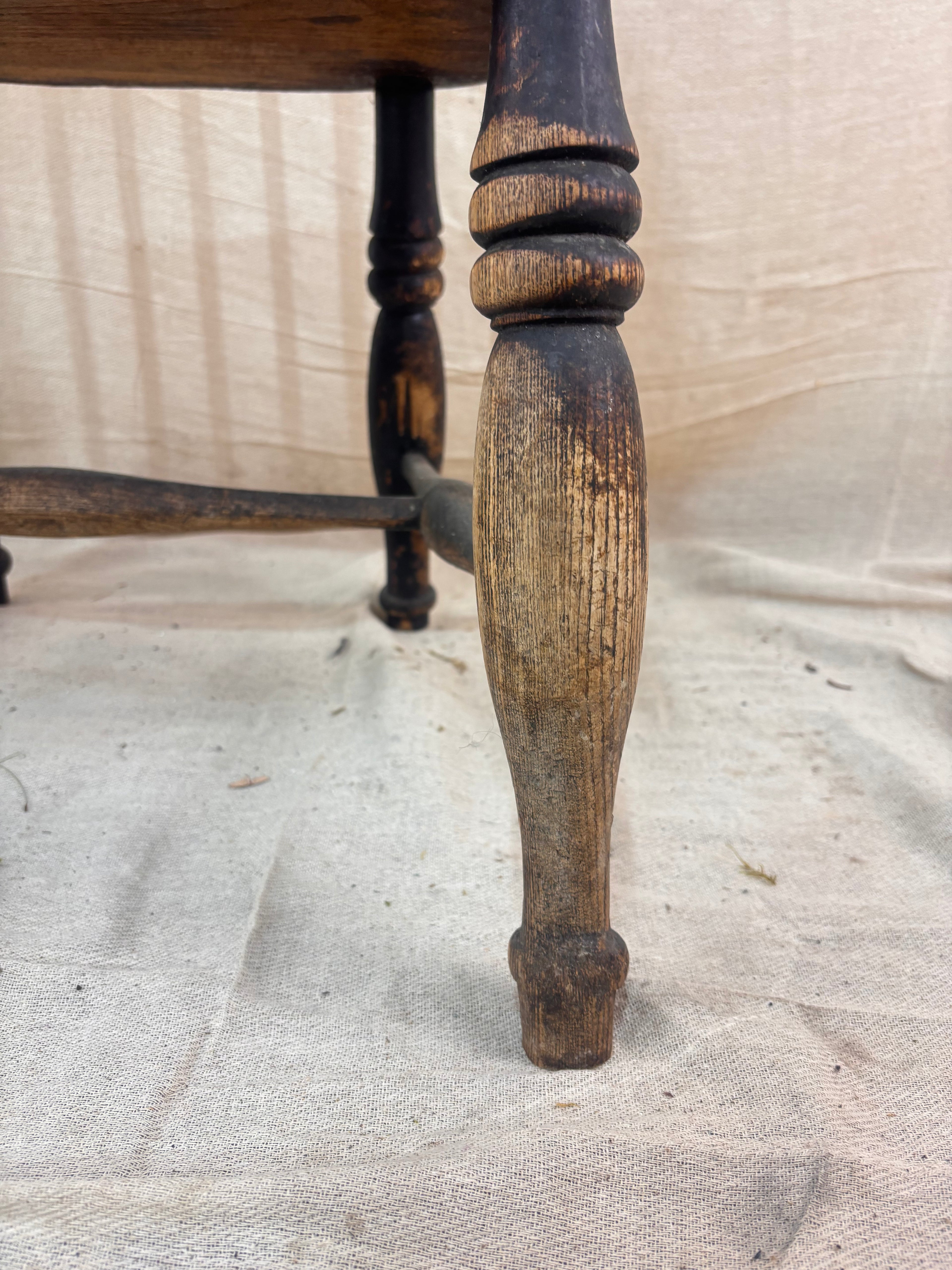 Windsor chair with hoop back, saddled seat, and splayed turned legs shown against a cream fabric background.