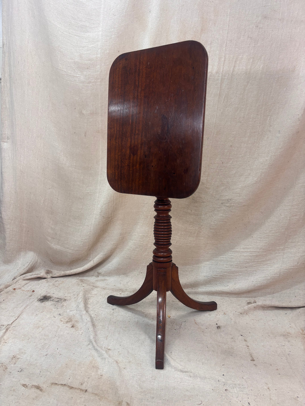 Wooden tripod table against a plain background