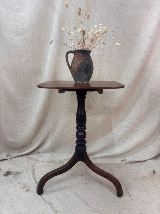 Wooden table with a vase of dried flowers on a draped fabric background