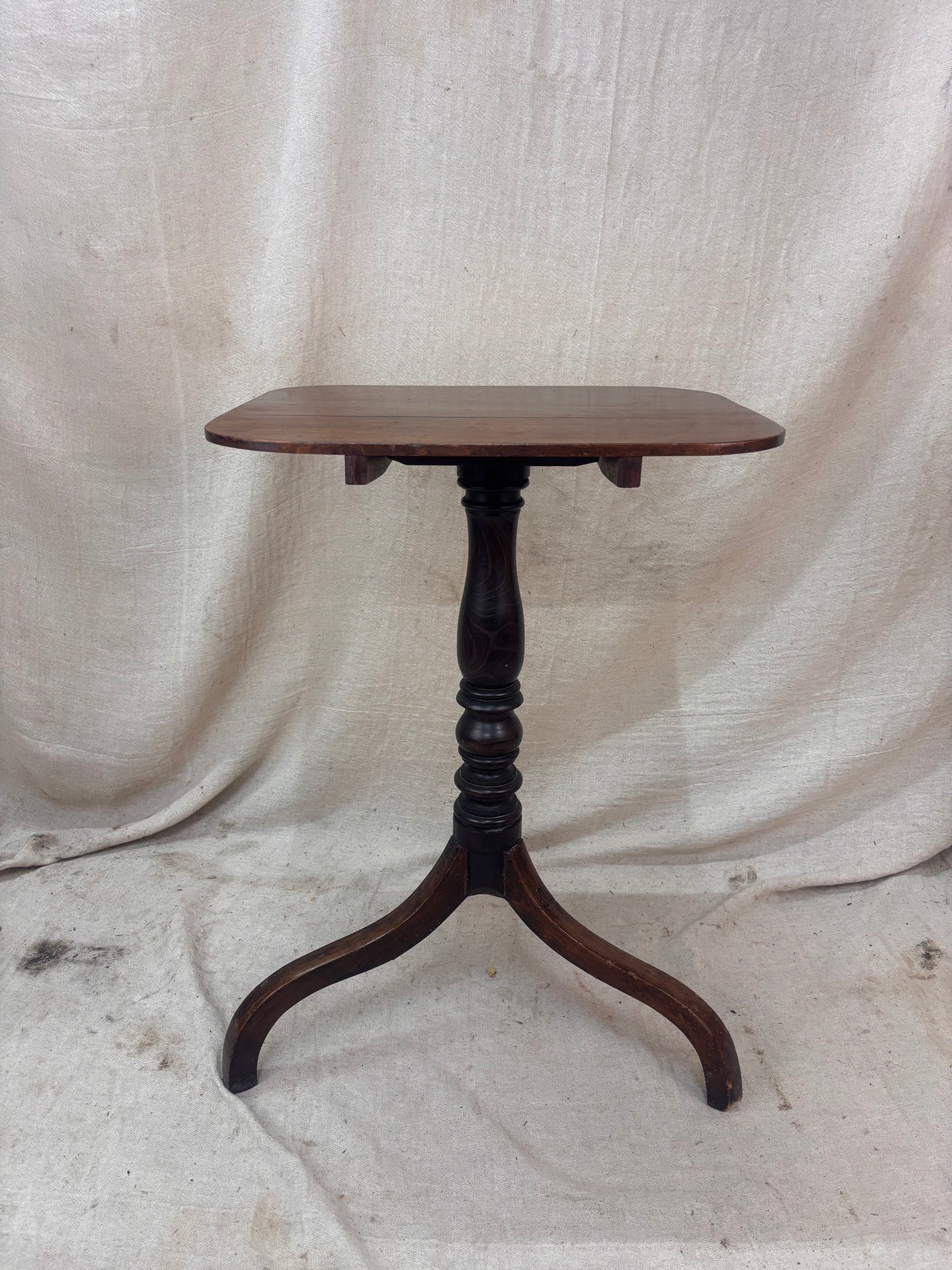 Wooden table with a single leg on a textured white background