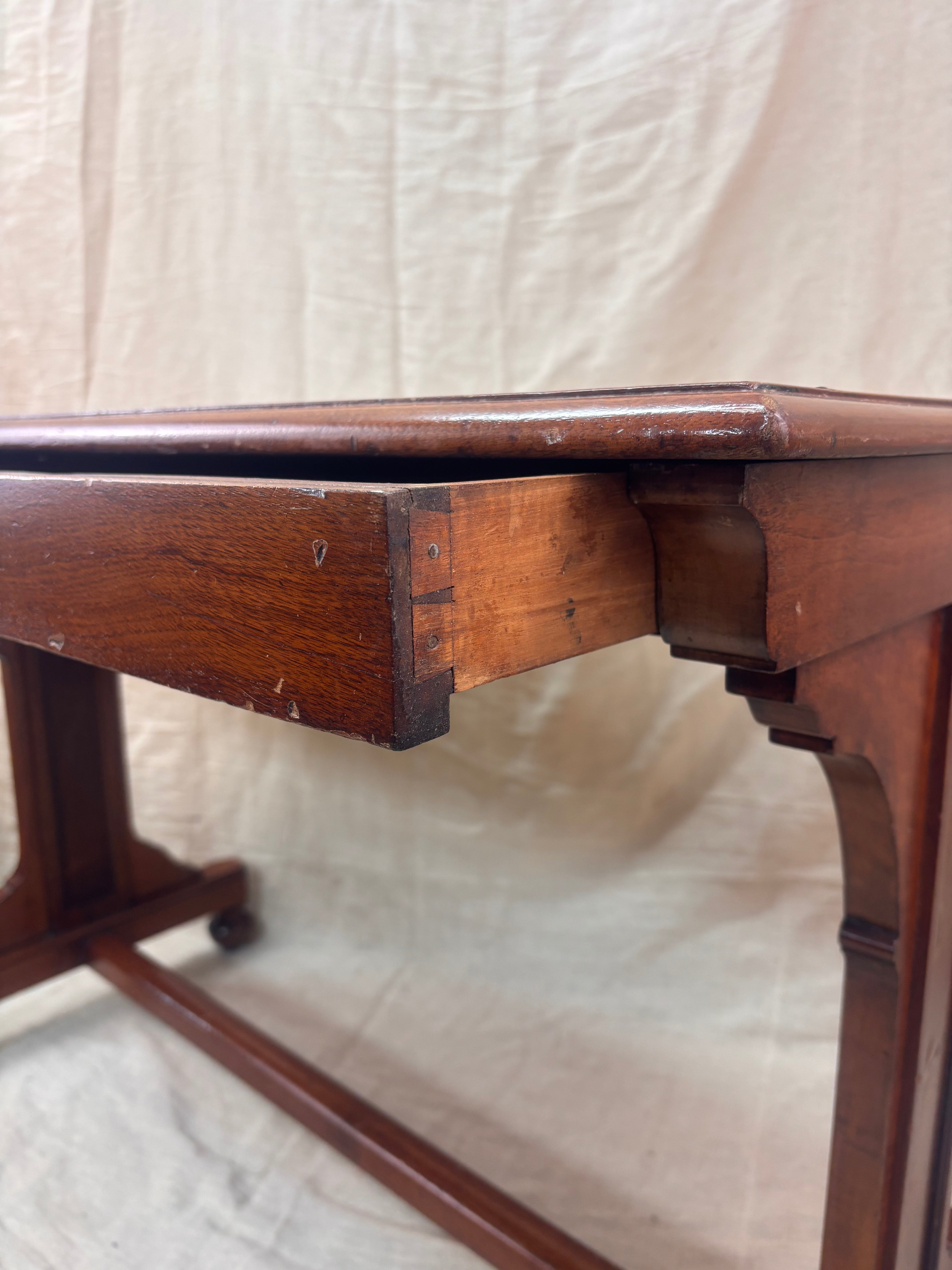 A small wooden table with a drawer against a cream background 