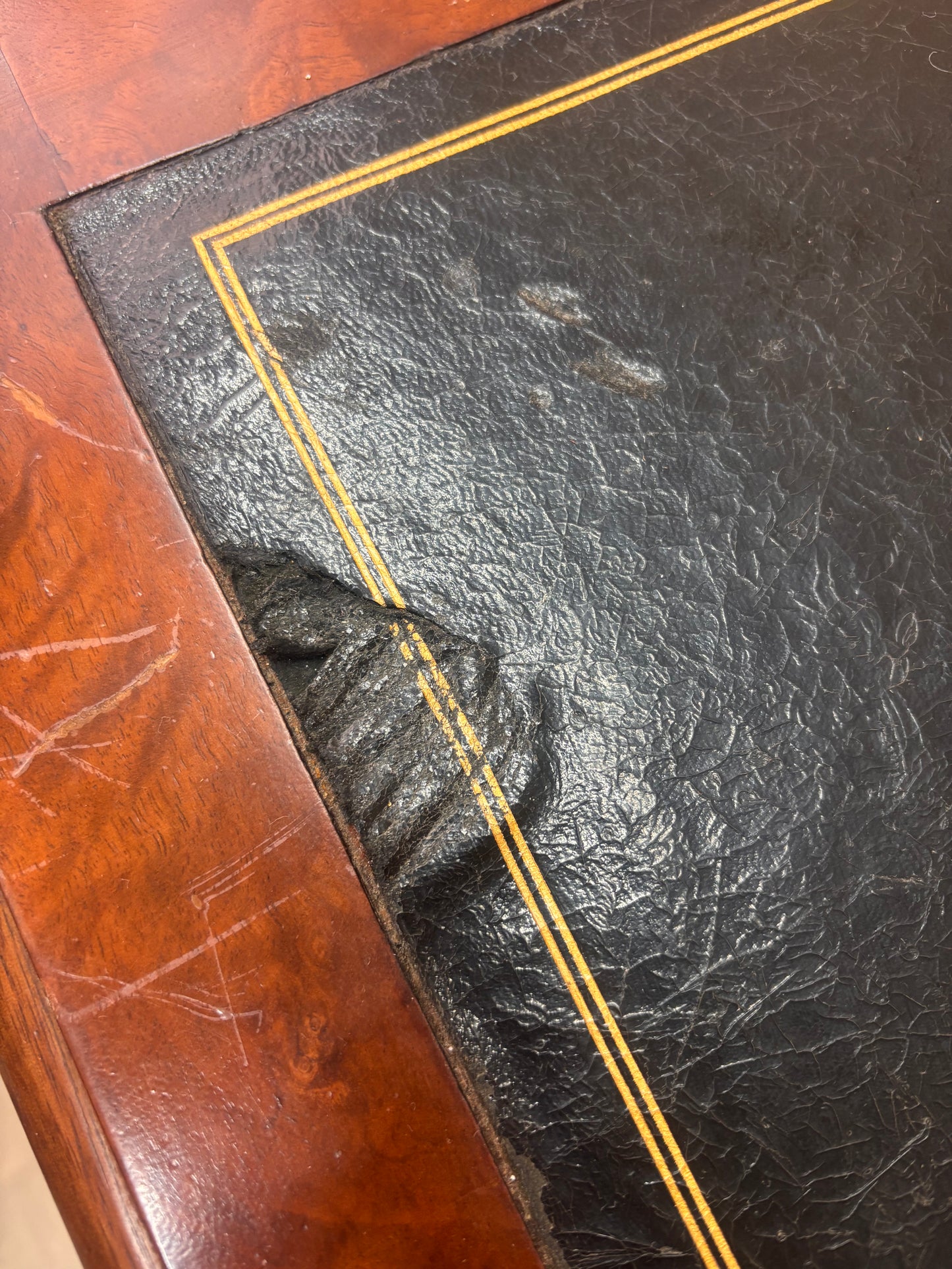 A small wooden table with a damaged leather top 