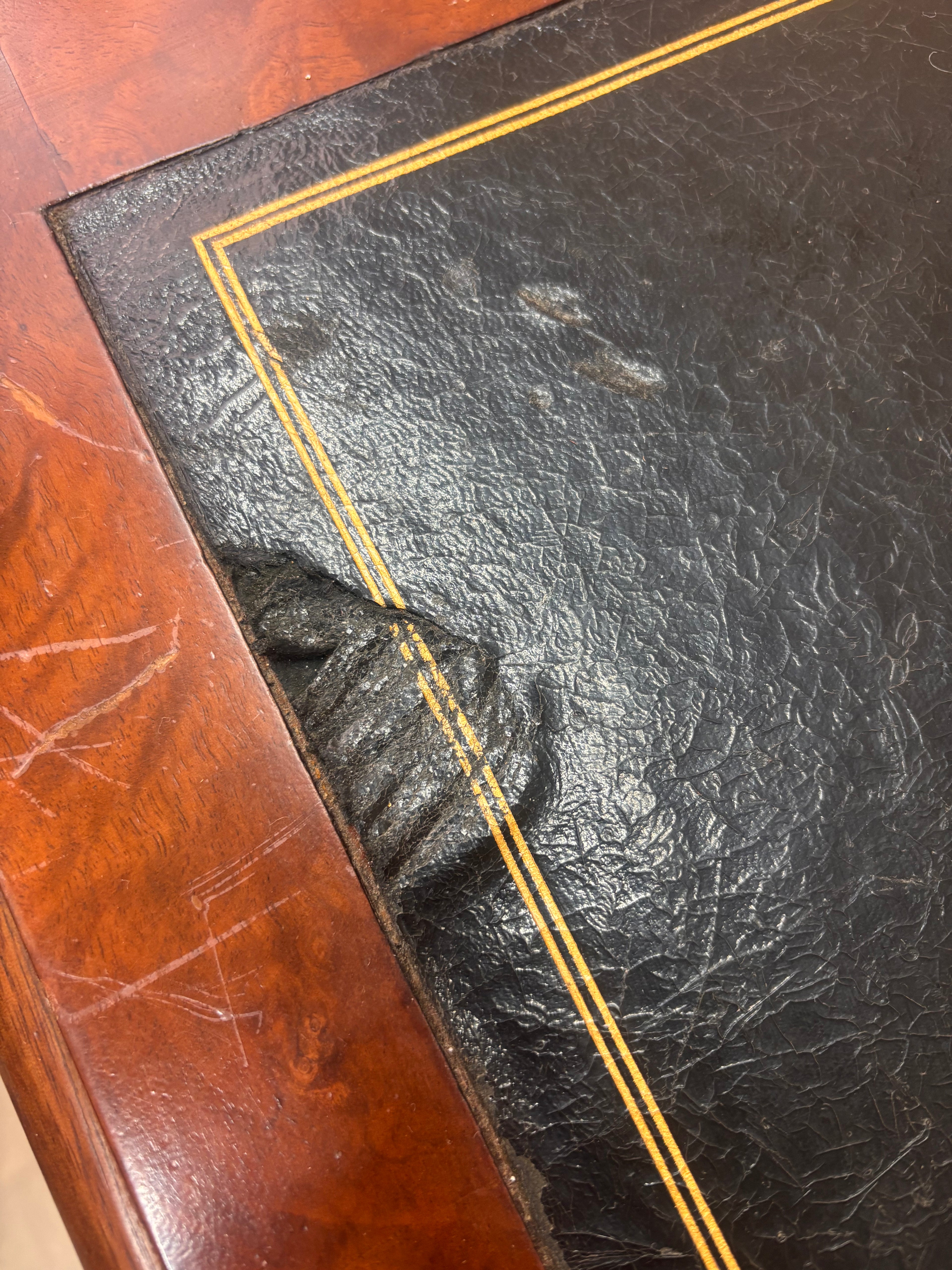 A small wooden table with a damaged leather top 