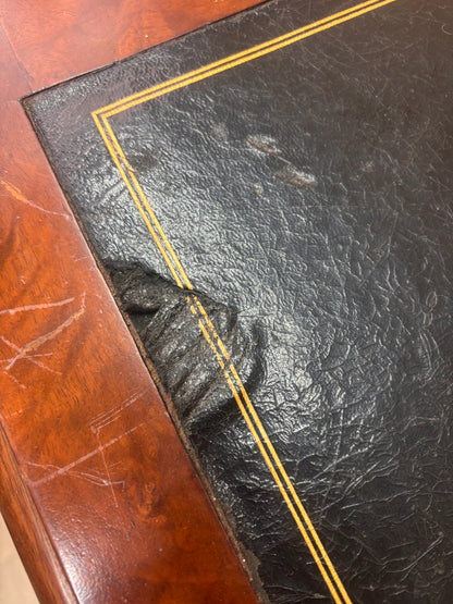 A small wooden table with a damaged leather top 