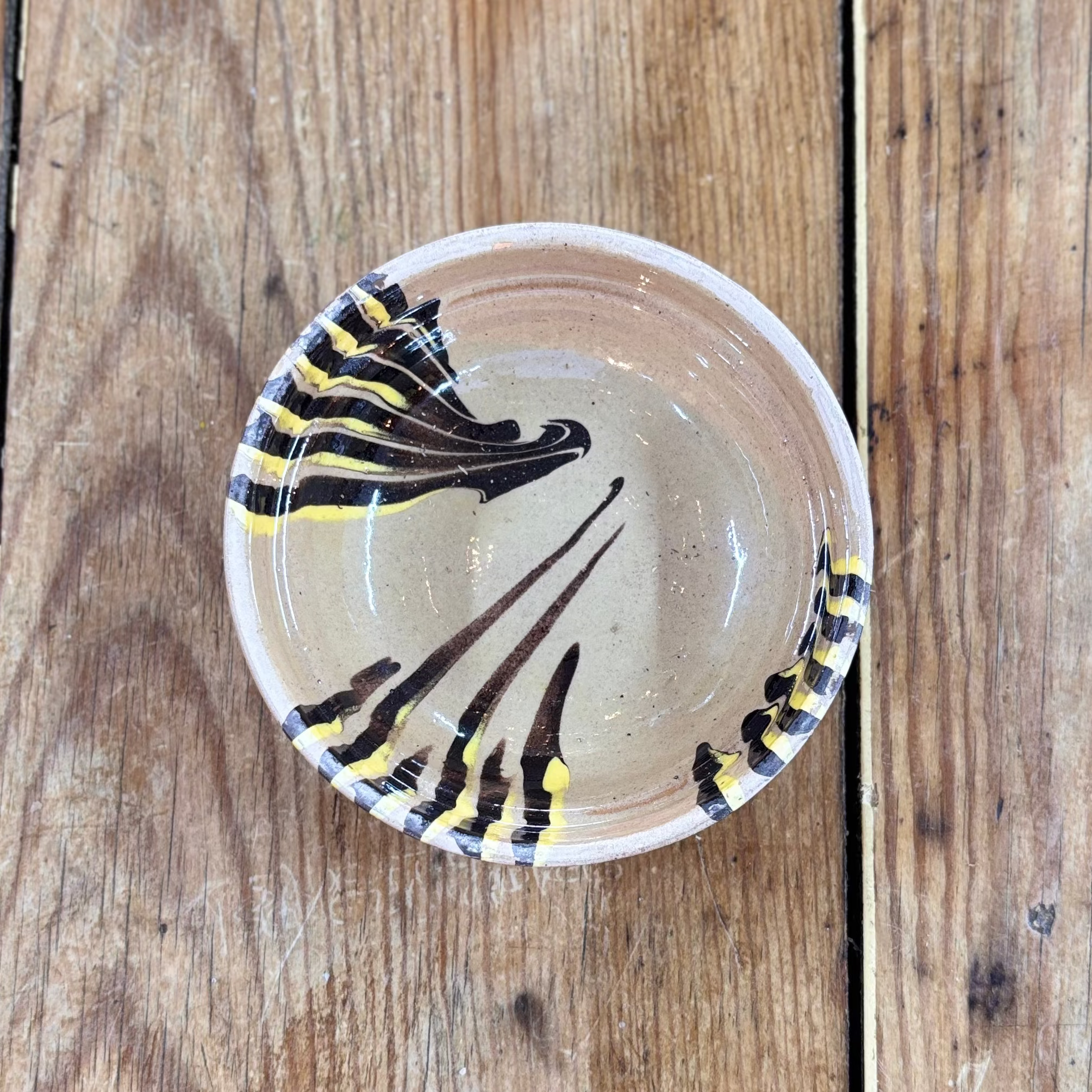 Decorative ceramic bowl with black and yellow pattern on a wooden surface
