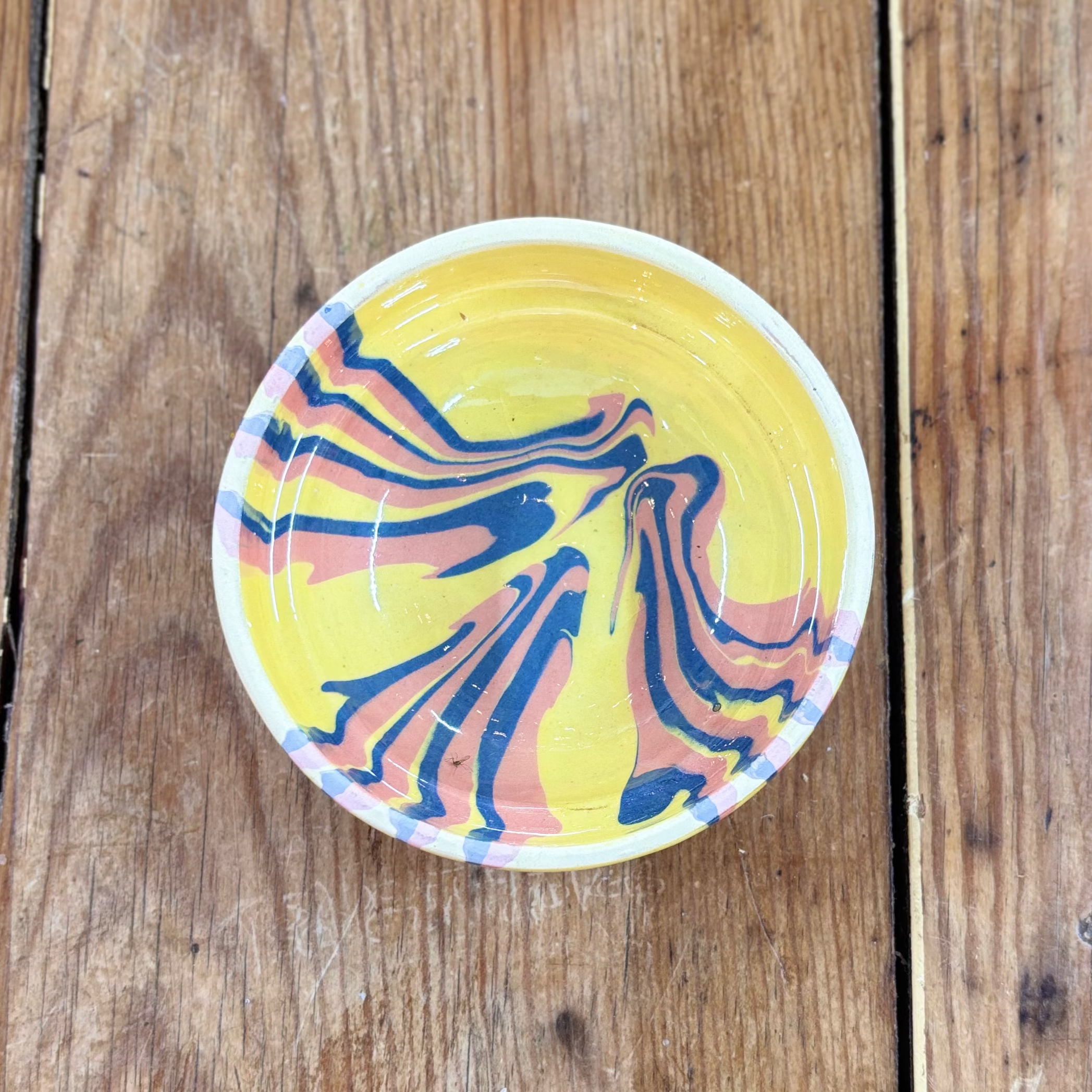 Colorful marbled design on a small round object against a wooden background