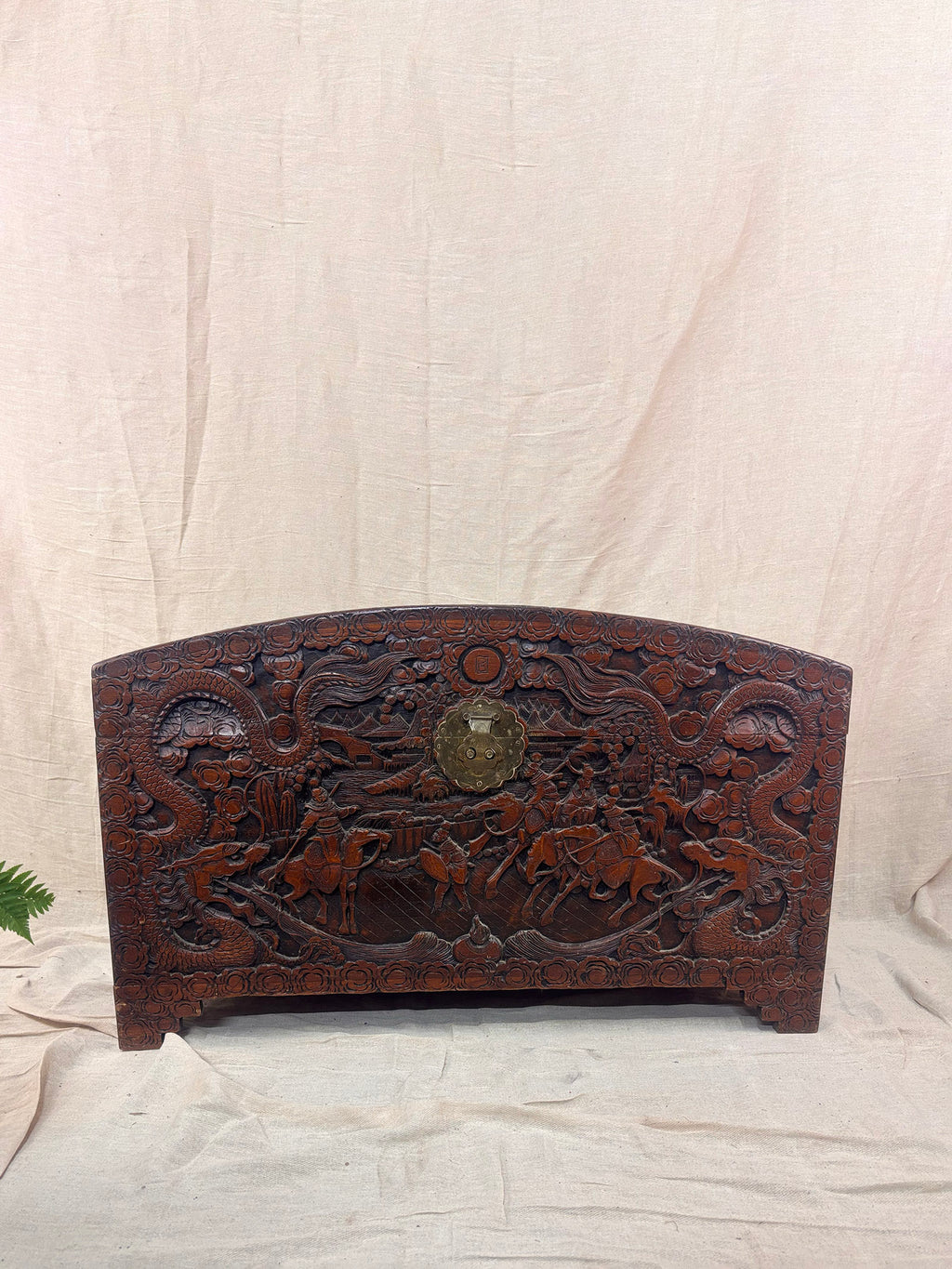 A detailed carved wooden chest on a cream cloth background