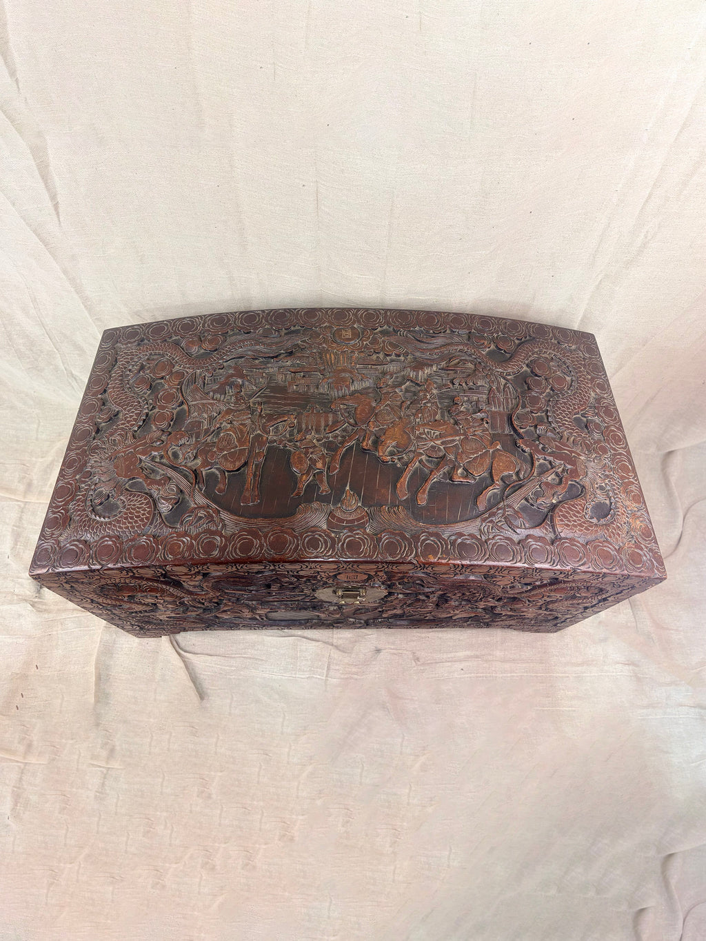 A detailed carved wooden chest on a cream cloth background
