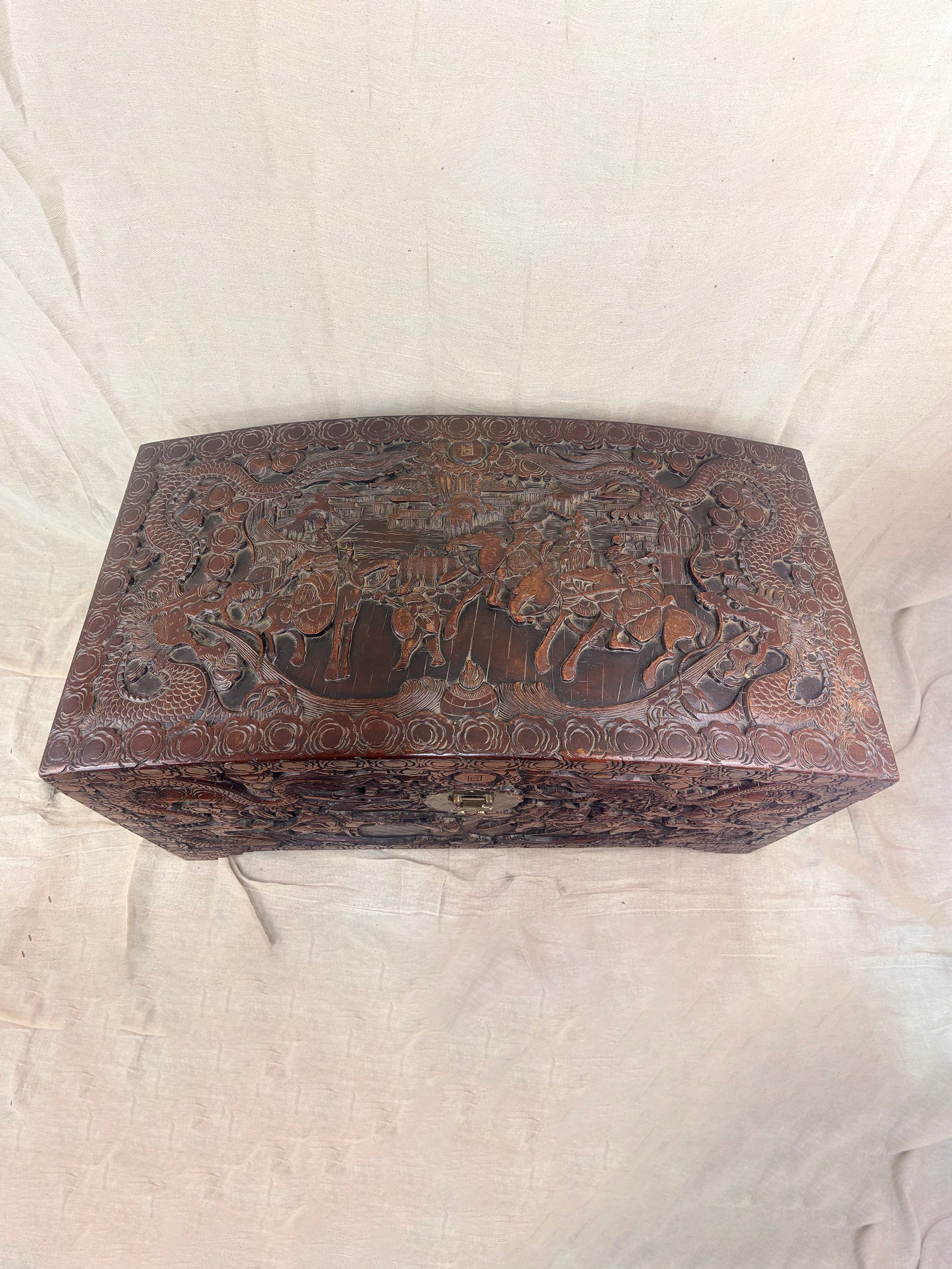 A detailed carved wooden chest on a cream cloth background