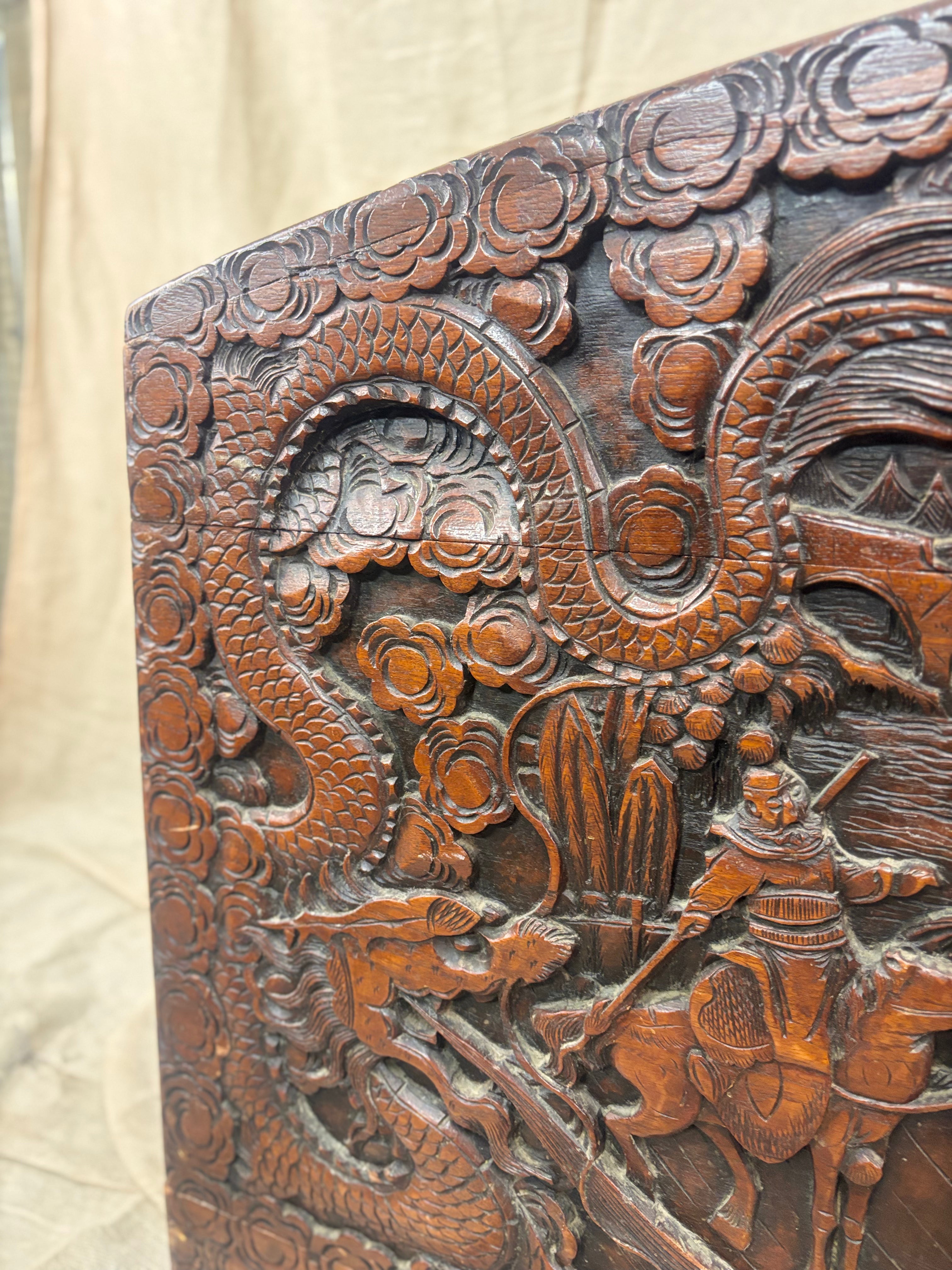 Close up detail of a carved wooden trunk with dragons, flowers and a man on horseback