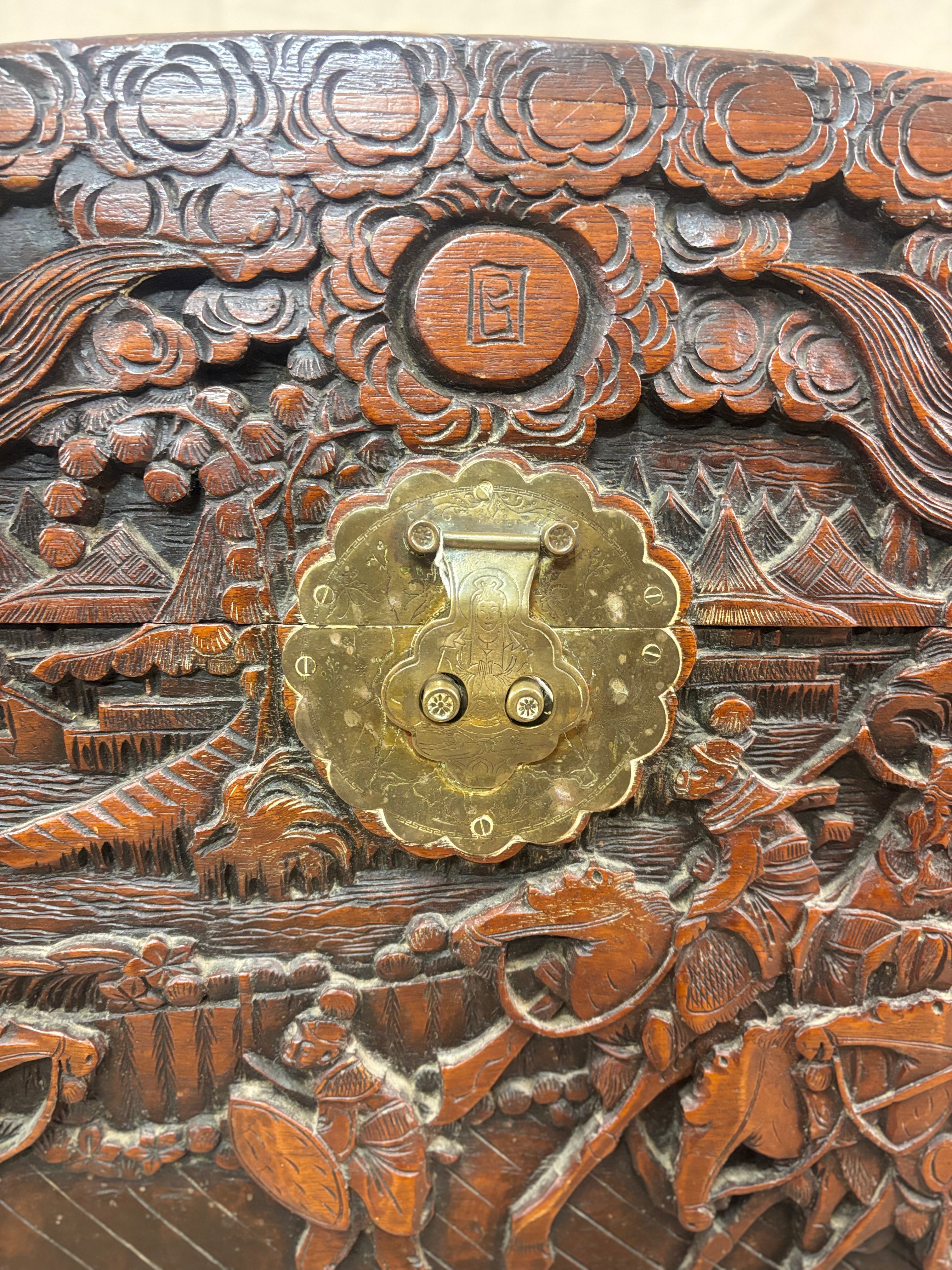 A brass clasp on a carved wooden chest with oriental scene
