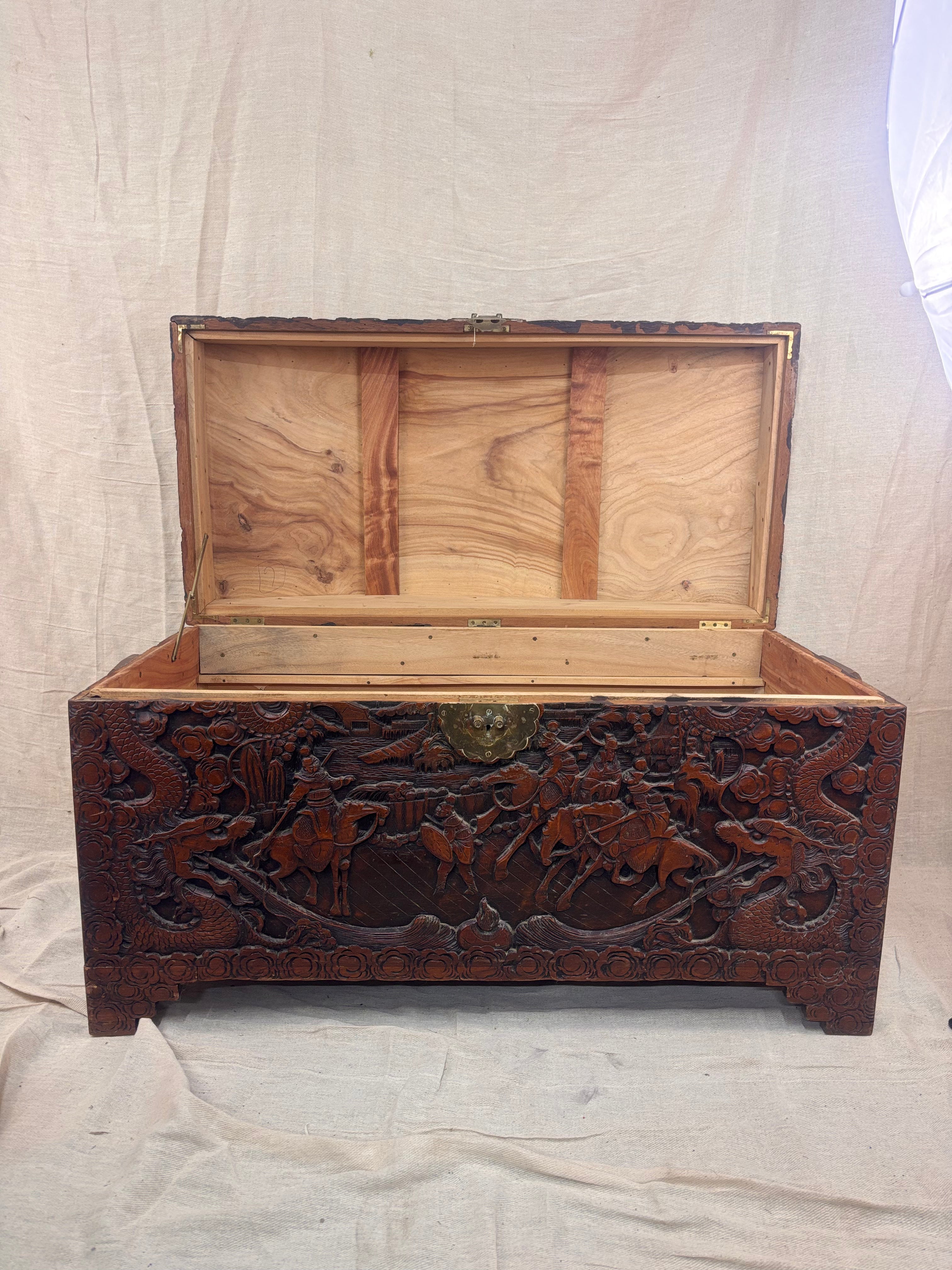 A carved wooden chest with the lid open on a cream background