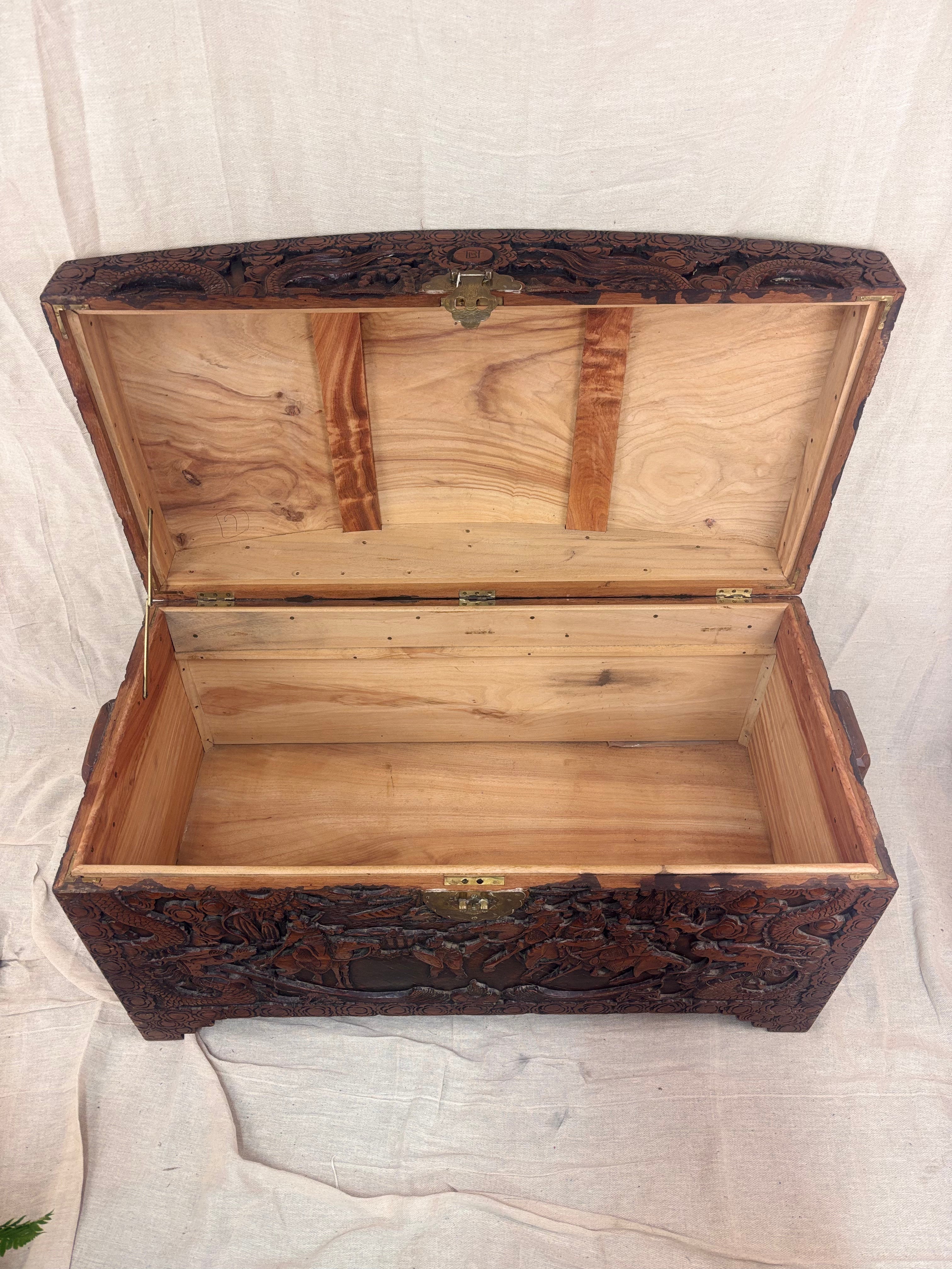 A carved wooden chest with the lid open showing an empty interior 