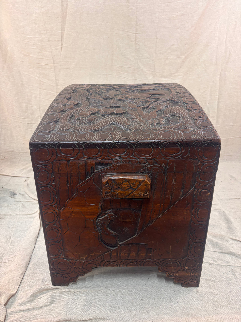A carved wooden chest with a curved lid and small handle
