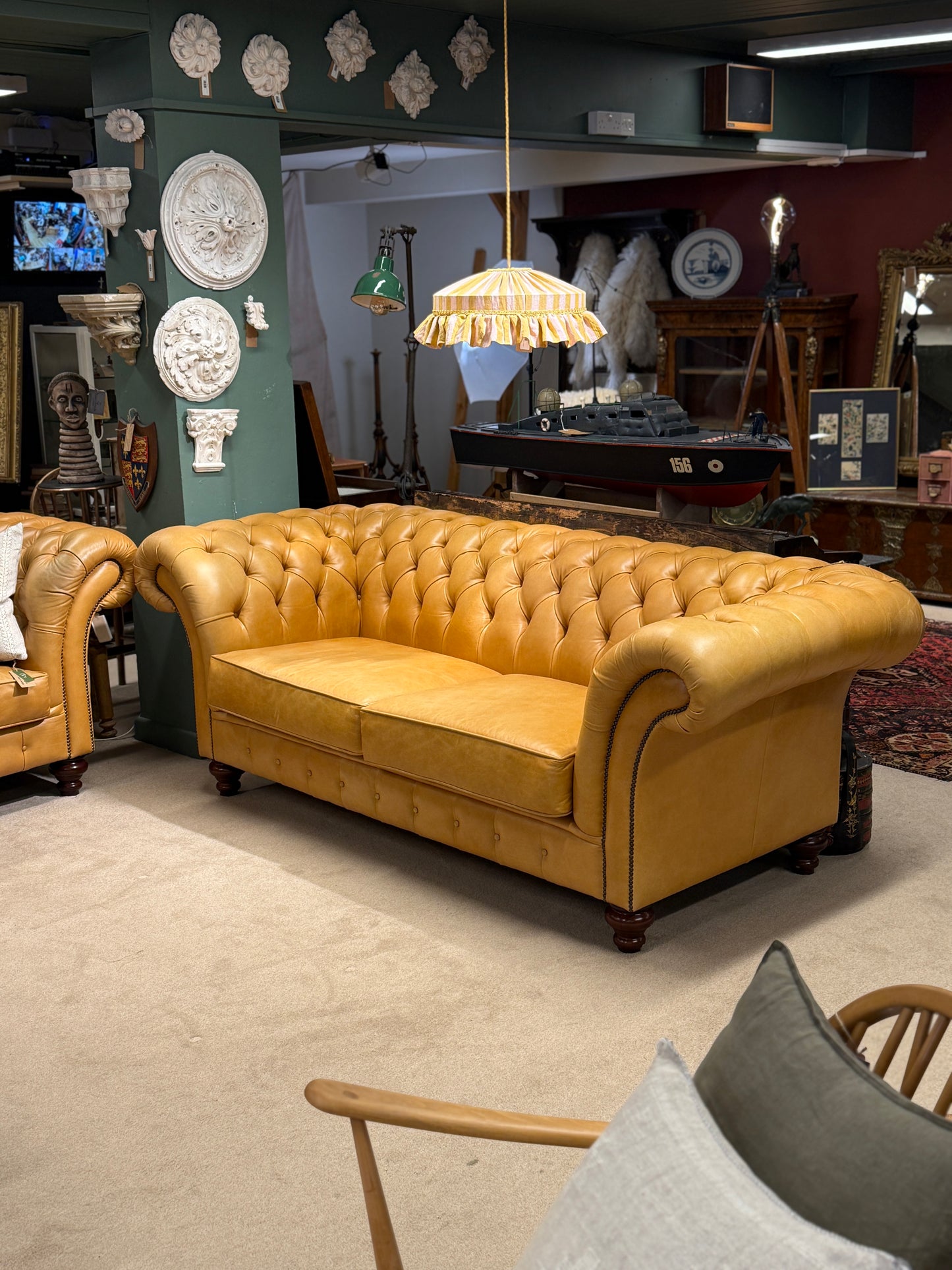 mustard leather sofa in a room with decorative items on the walls and floor.