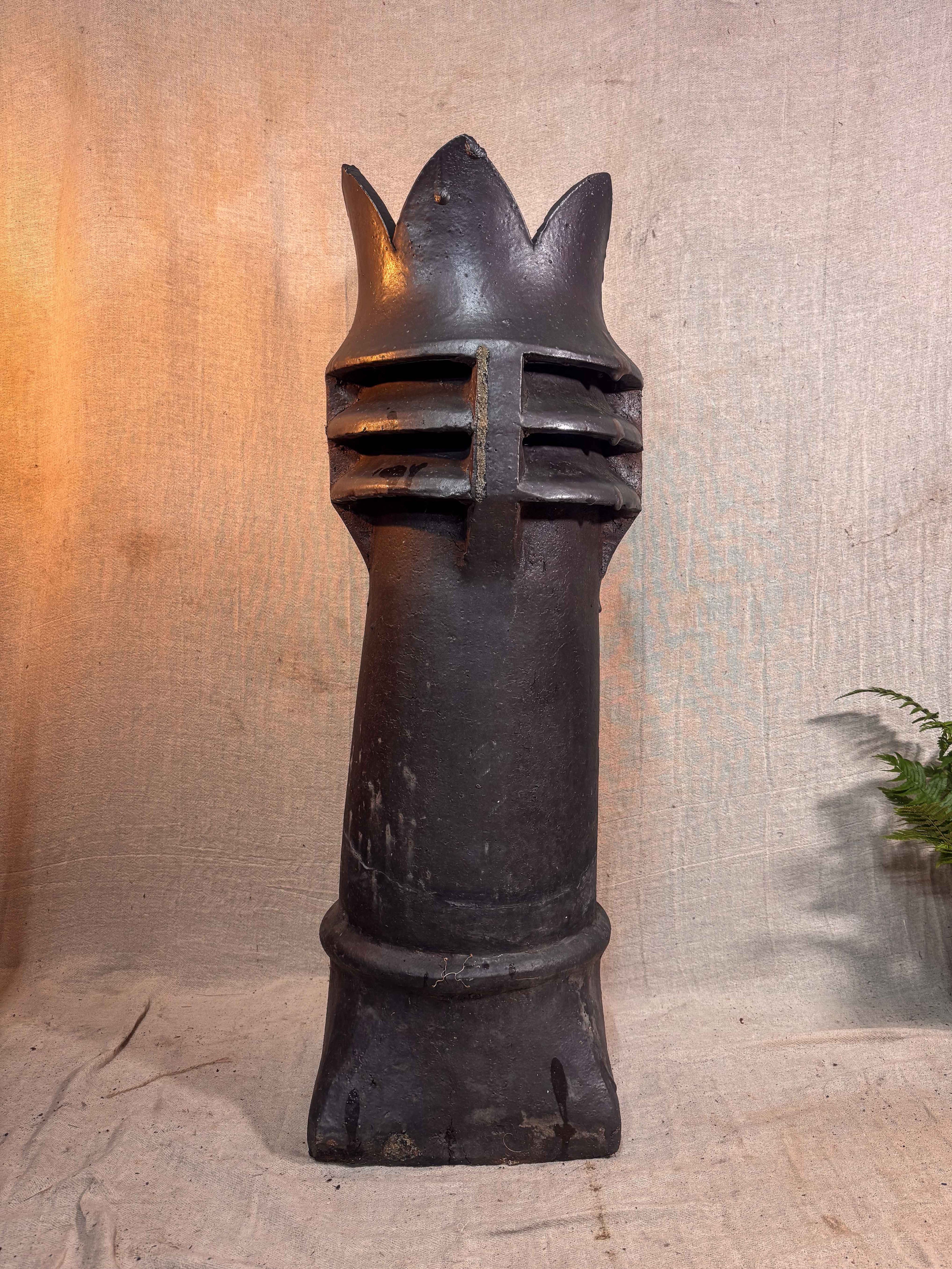Decorative black metal chimney pot on a textured beige background
