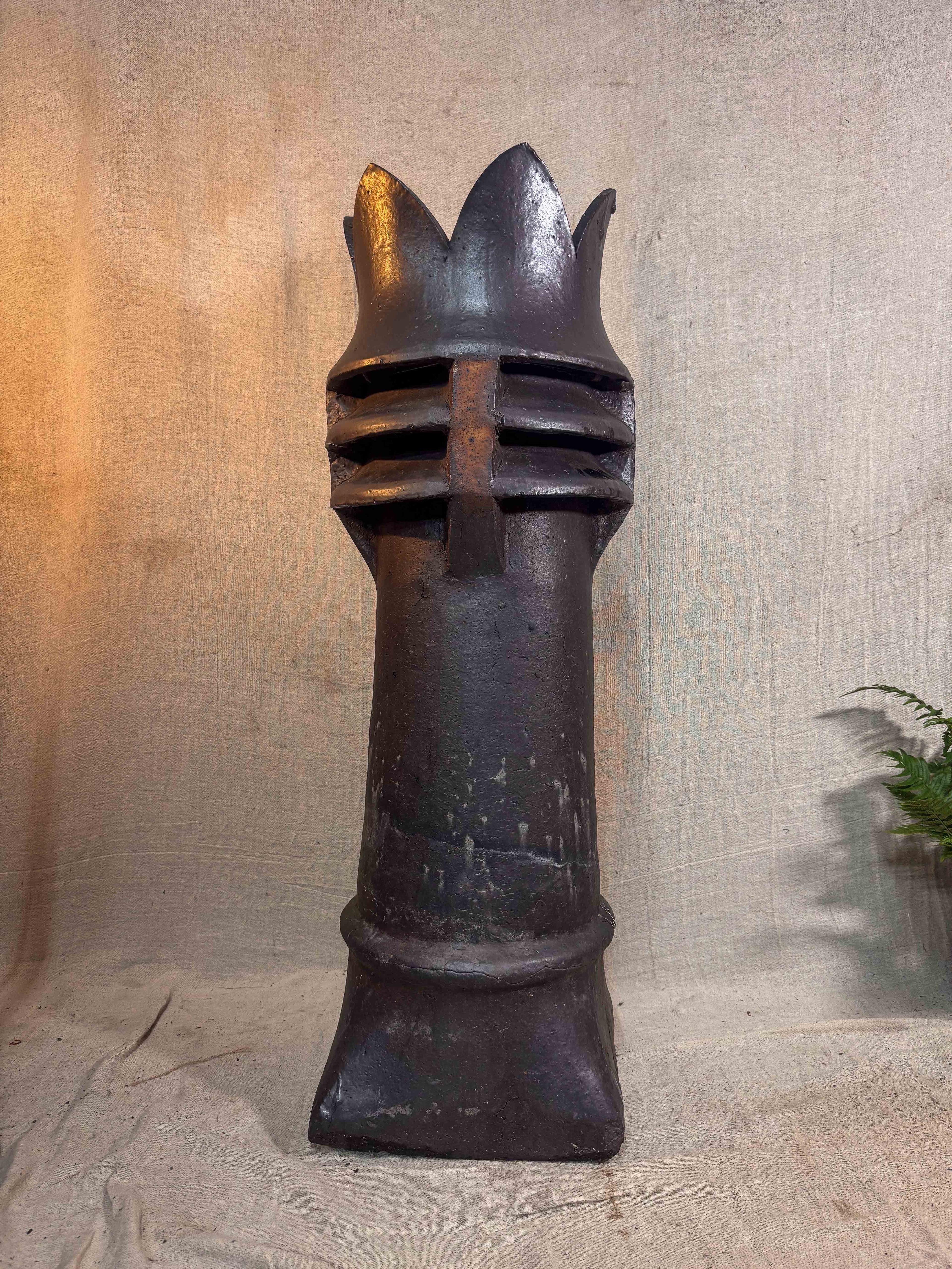 a brown glazed chimney pot on a beige cloth backdrop
