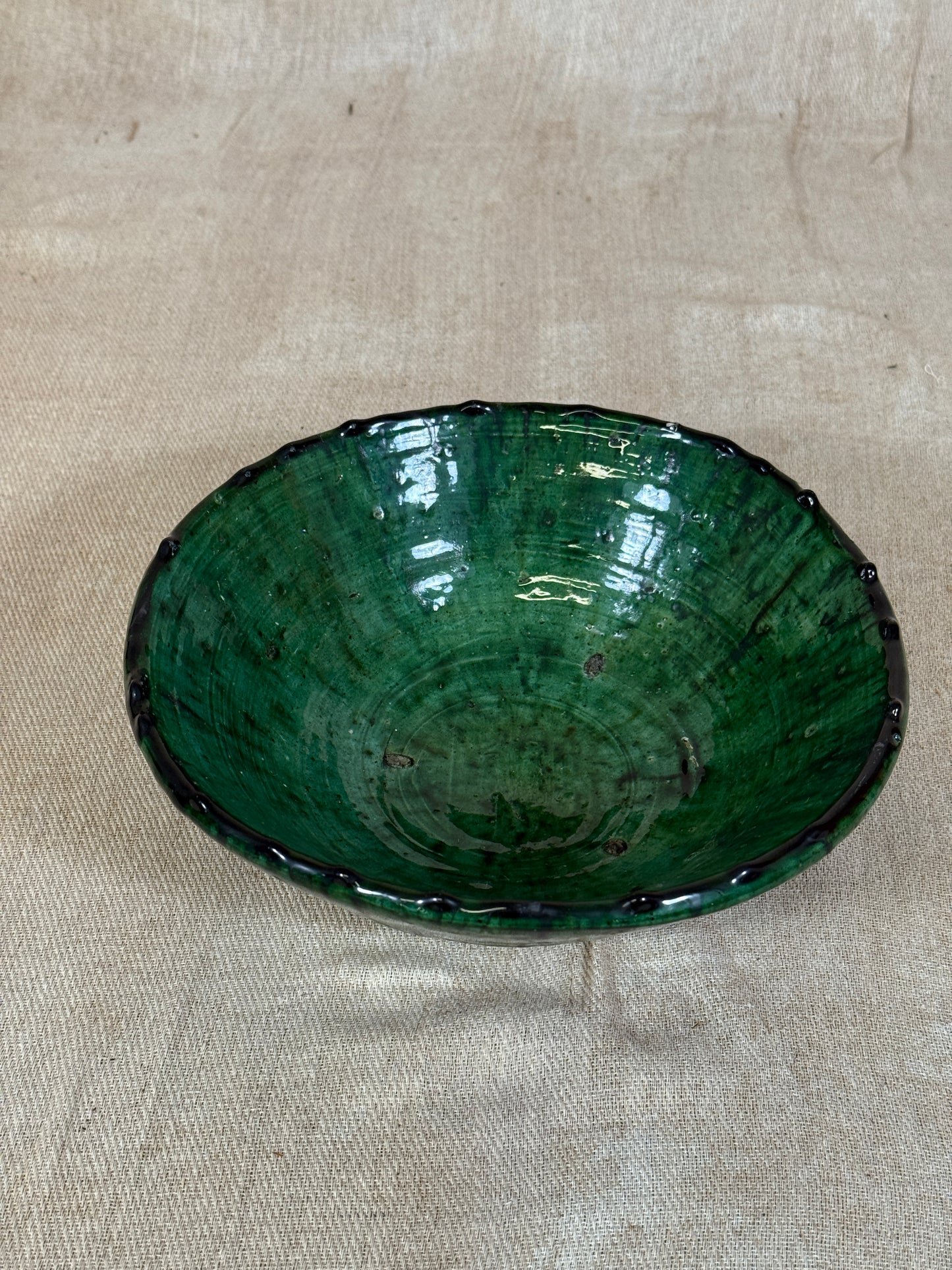 Green ceramic plate on a beige fabric background