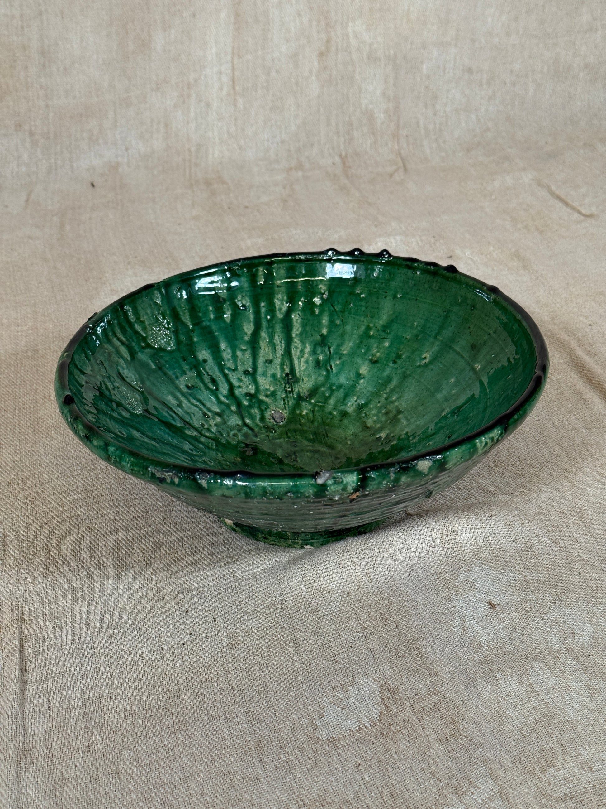 Green ceramic bowl on a beige fabric background