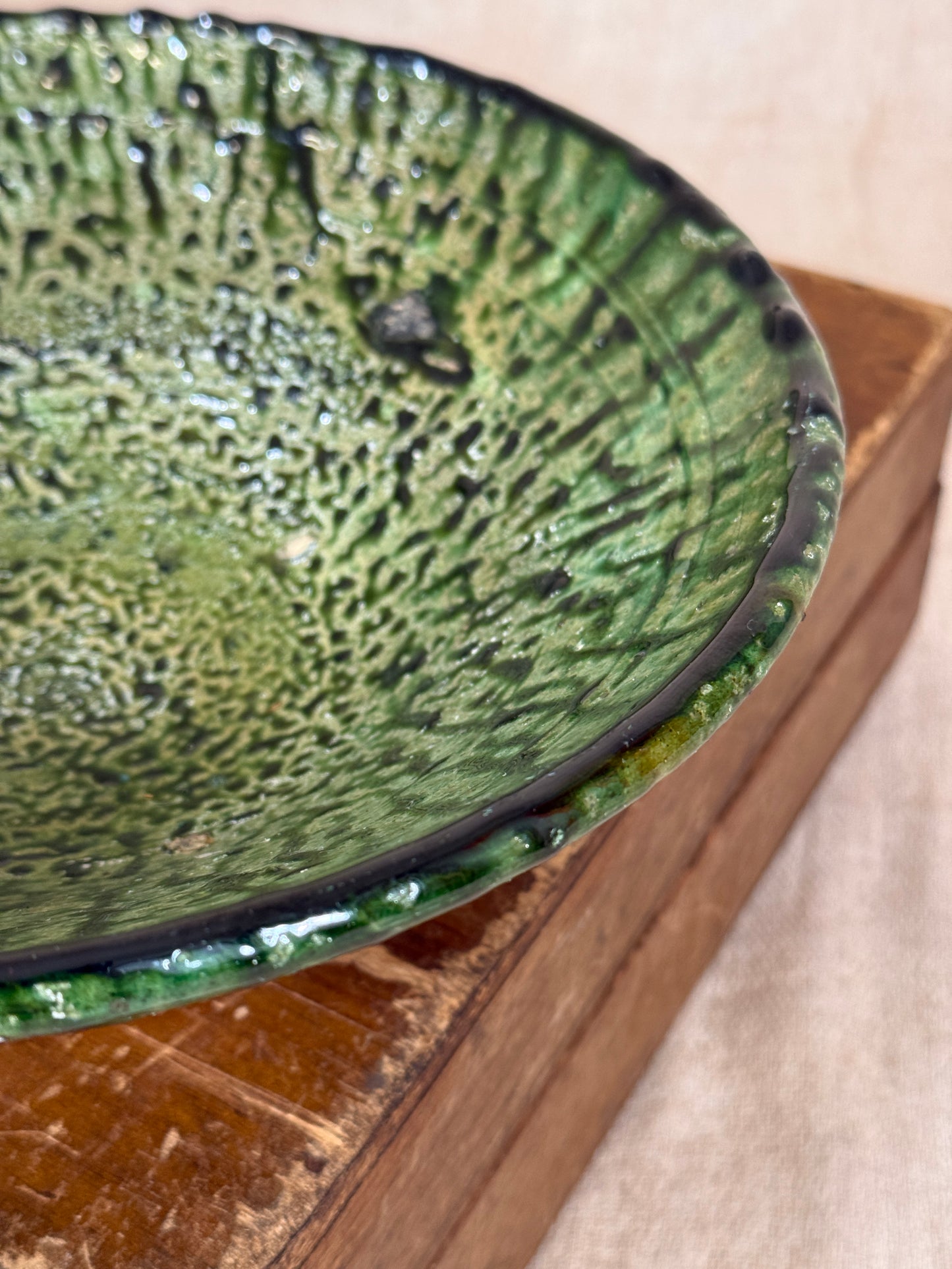 Green ceramic bowl with textured surface on a wooden surface