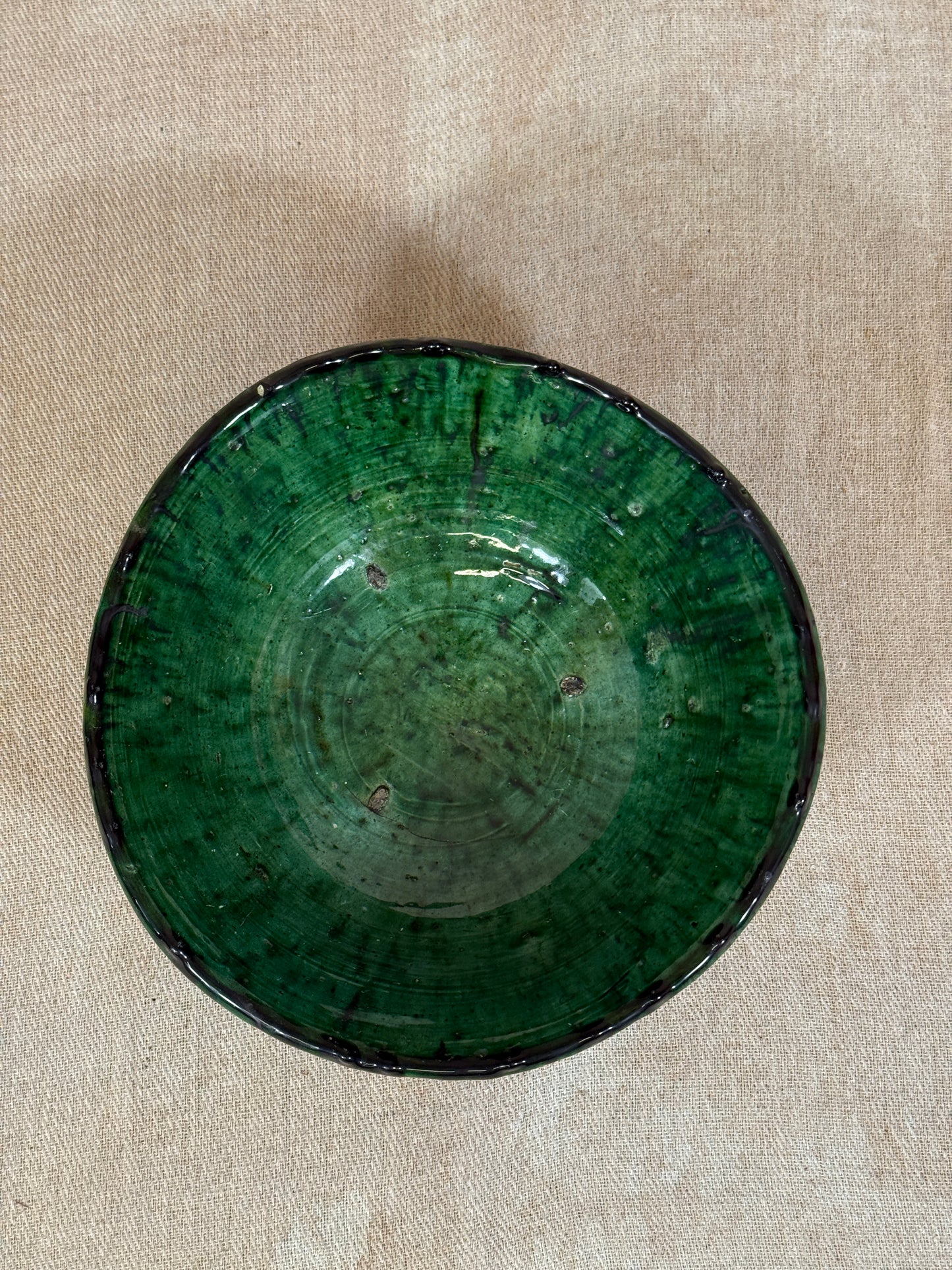 Green ceramic bowl on a beige fabric background
