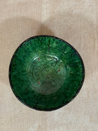 Green ceramic bowl on a beige fabric background