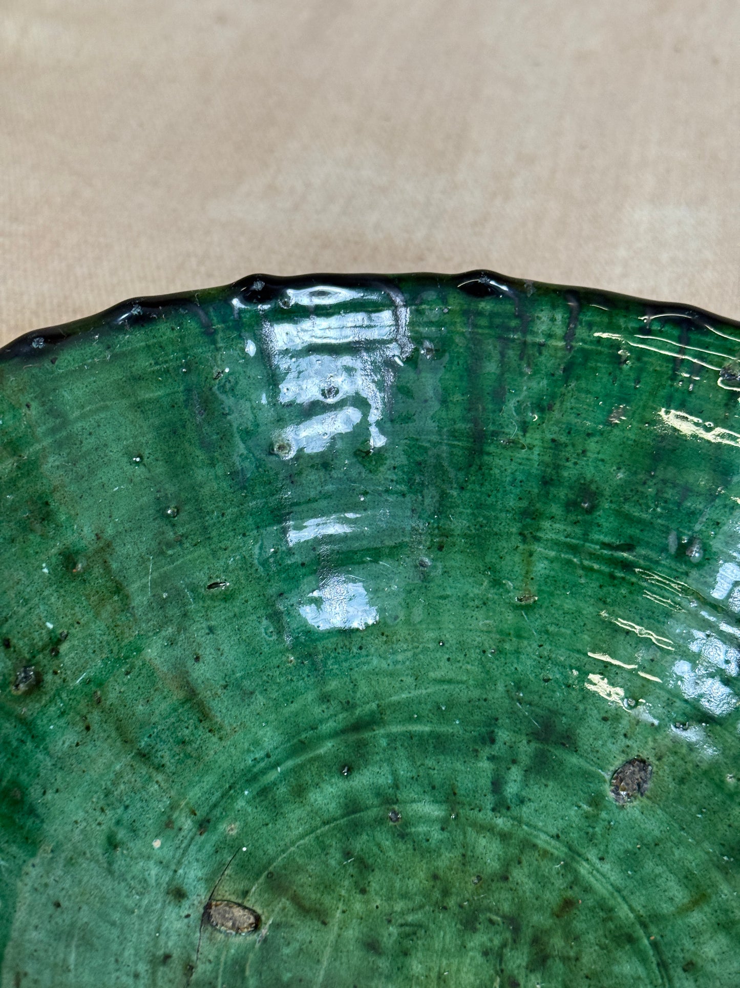 Close-up of a green ceramic plate with visible branding on a beige background