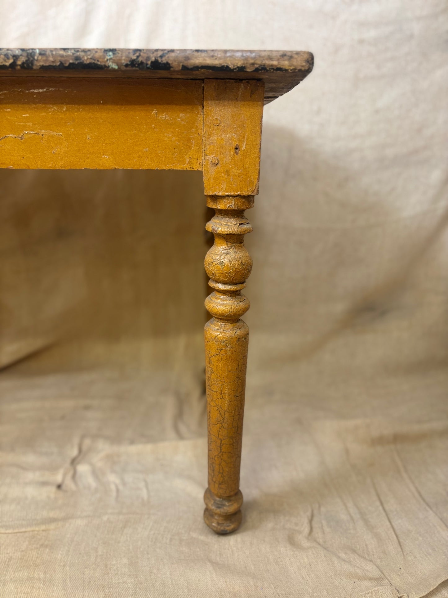 Wooden table leg with a worn finish on a textured beige background