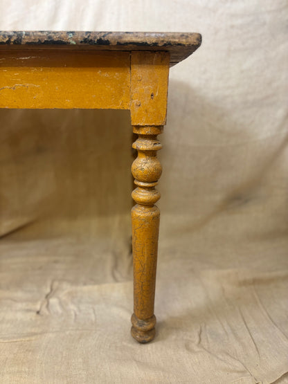 Wooden table leg with a worn finish on a textured beige background