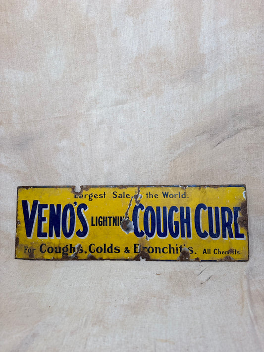 Vintage-style yellow and blue sign for 'Venos Cough Cure' on a textured beige background