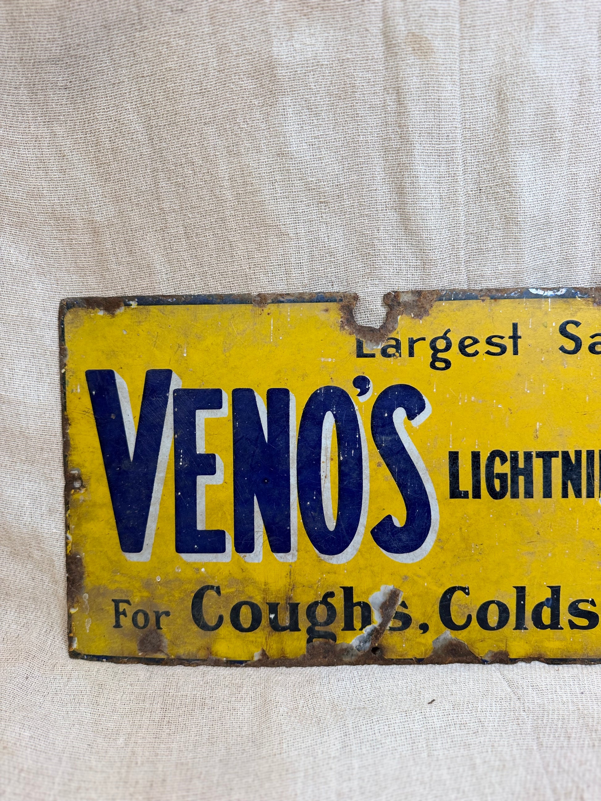 Vintage sign for Veno's Lightning Cough and Cold remedy on a textured beige background
